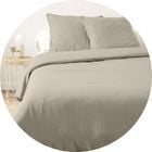 Lit habill&eacute; de linge de lit clair dans une chambre.